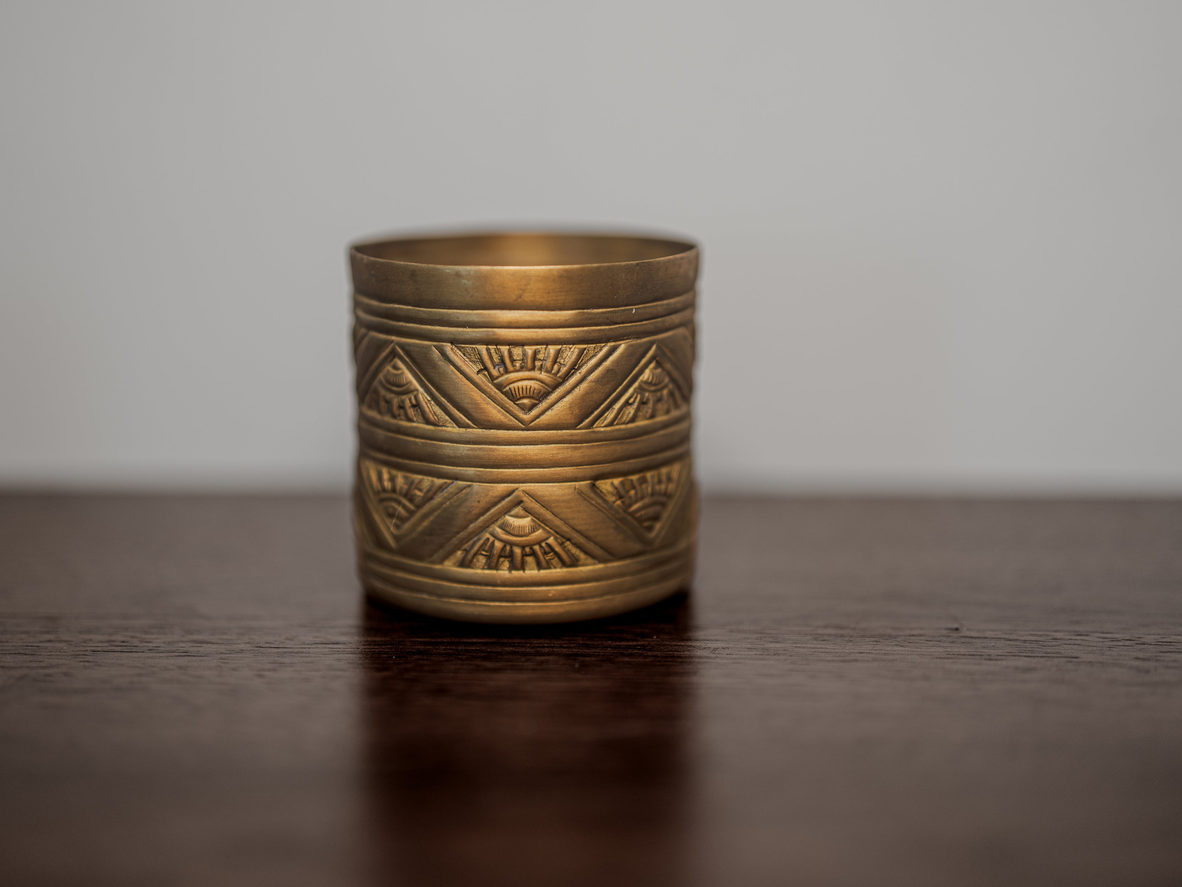 Brass candle with geometric patterns on a wooden surface