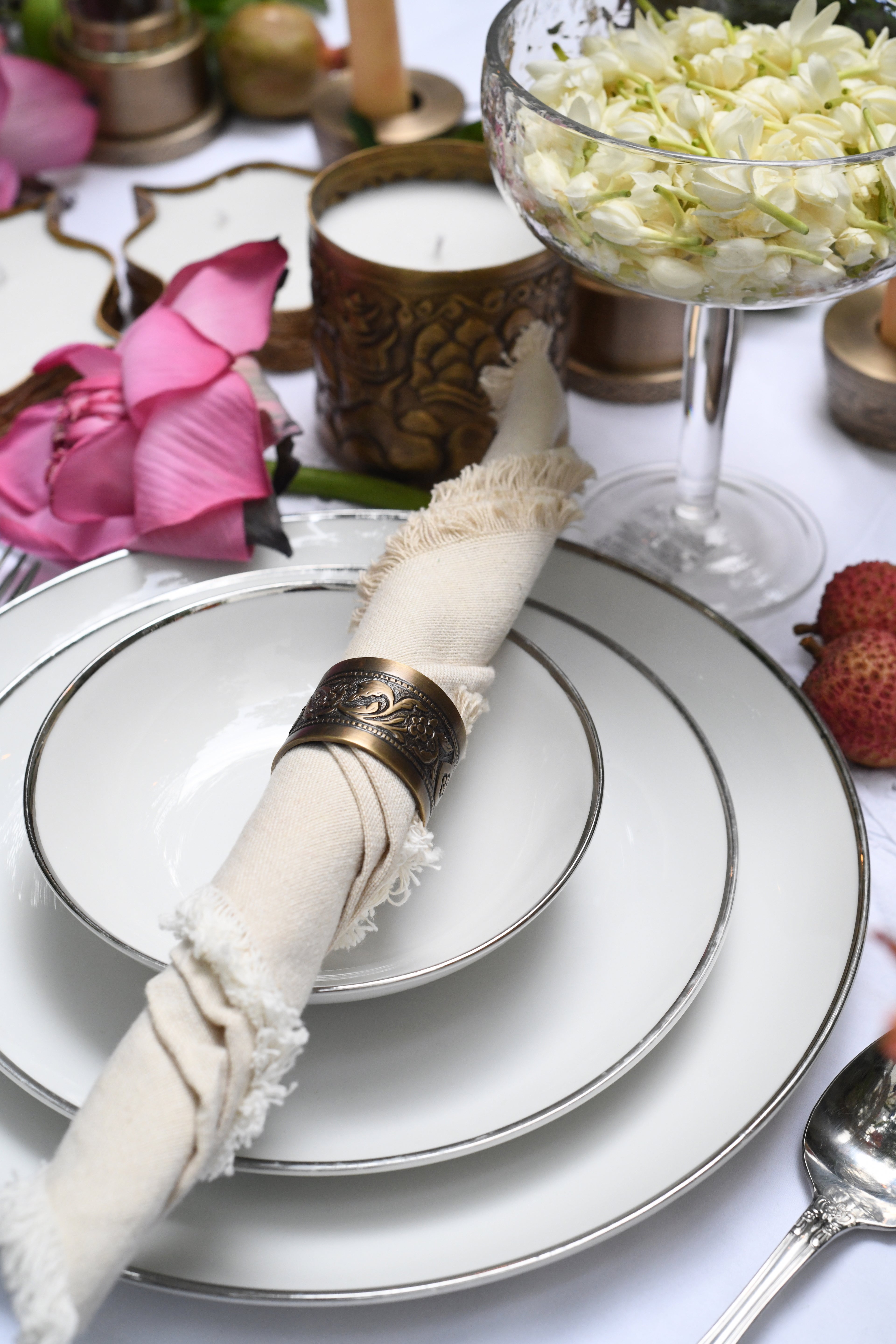 Elegant table setting with white napkin, gold napkin ring, and decorative elements.