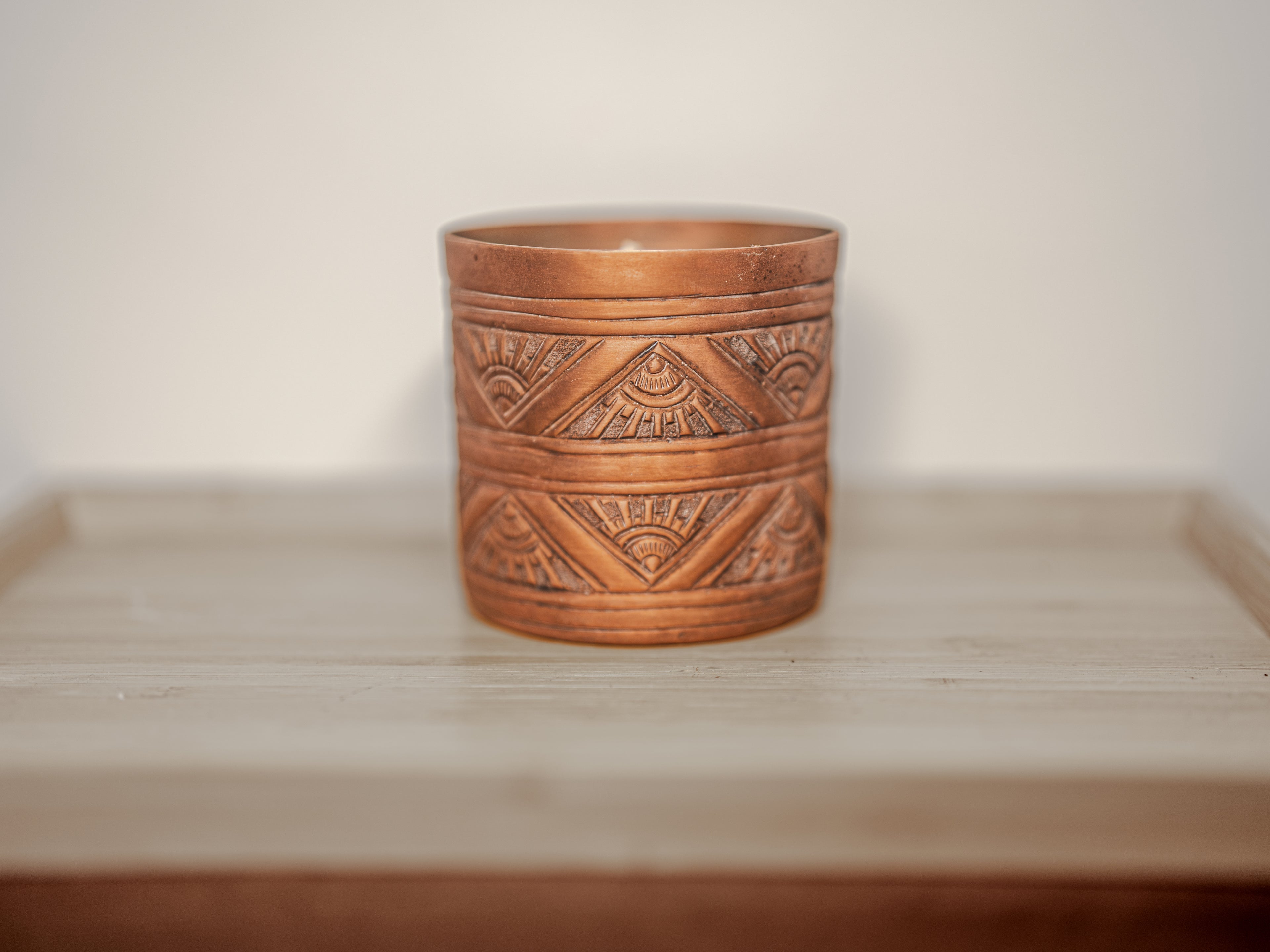 Copper Candle with geometric patterns on a wooden surface