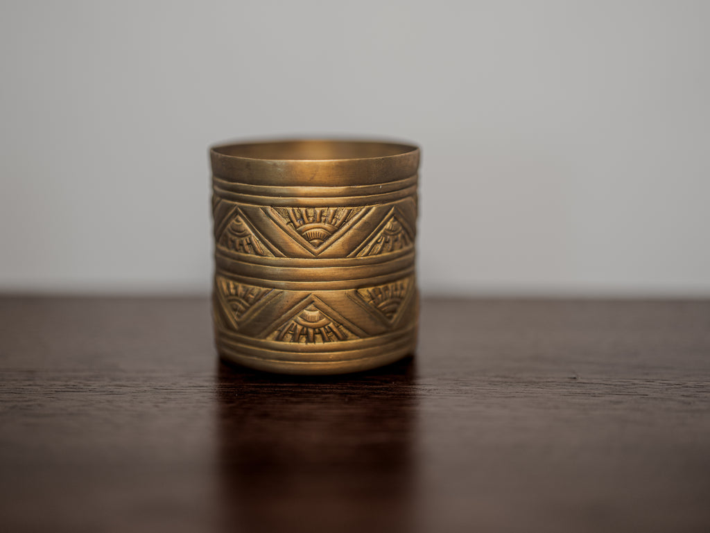 Brass candle with geometric patterns on a wooden surface