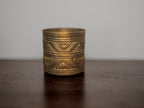 Brass candle with geometric patterns on a wooden surface